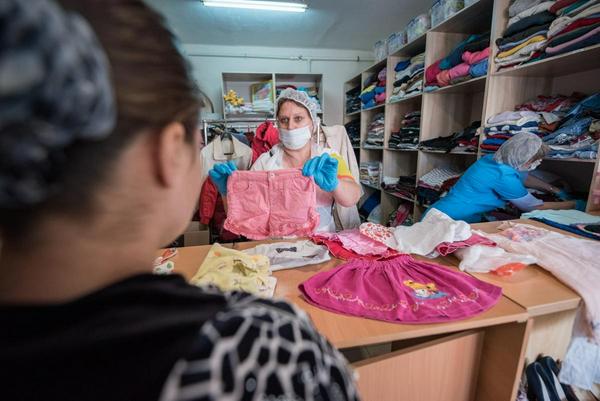 2022年5月24日，俄罗斯新沙赫京斯克：一名教会志愿者在俄罗斯东正教教会（莫斯科宗主教区）沙赫蒂教区在新沙赫京斯克顿神像教堂的乌克兰难民援助中心向一名来自乌克兰的难民妇女分发衣服